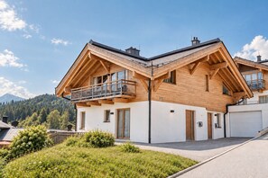 A modern two-story house with a wooden facade, a balcony, and a garage.