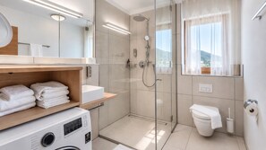 Une salle de bain moderne avec une douche à parois de verre, un lavabo blanc et des toilettes.