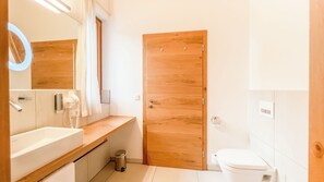 A modern bathroom with a wooden door, a white sink, and a mirror.