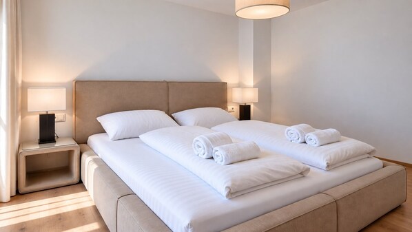 Una habitación de hotel con una cama grande, dos mesitas de noche y una lámpara a cada lado.