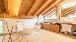 Une salle de bain rustique, avec des murs en bois, comprenant une baignoire sur pieds, des toilettes et un lavabo.