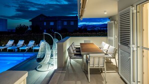 A rooftop terrace with a pool, lounge chairs, a table, and a view of a building in the background. - Luxury villa Bachin - family villa (Kastela)