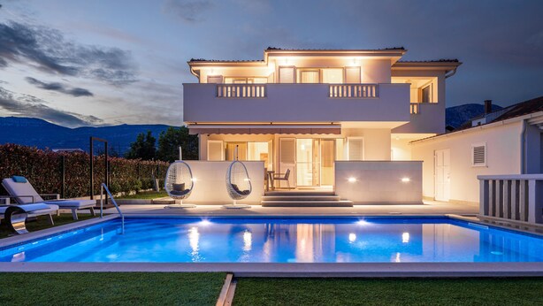 A modern two-story house with a swimming pool, outdoor seating, and a view of mountains. - Luxury villa Bachin - family villa (Kastela)