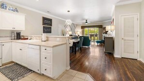 A spacious kitchen with white cabinetry, a central island, and a dining area with a table and chairs. - Kings Hideaway - Near DT! (Branson)