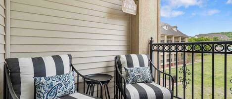 A balcony with two black and white striped sofas, a small round table, and a decorative sign reading "The Porch."