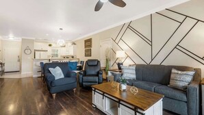 A modern living room with a dark wood floor, a blue sofa, a grey sofa, a black leather chair, and a wooden coffee table. - Kings Hideaway - Near DT! (Branson)