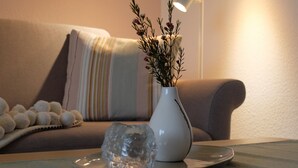 A modern living room with a white vase containing dried plants on a wooden table, a grey plate, and a decorative glass object. - Apartment "Meine Auszeit", 2 adults + 1 infant, 1 bathroom, terrace, WLAN (Koserow)