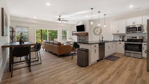 A modern kitchen with white cabinets, stainless steel appliances, and a dining area with a wooden table and chairs. - New Lakeview Penthouse - Amenities Galore! (Branson)