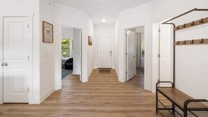 A hallway with wooden flooring, white walls, and a bench on the right. - New Lakeview Penthouse - Amenities Galore! (Branson)