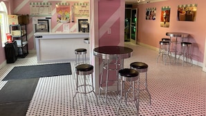 A pink-themed café with a counter, stools, and a patterned floor. - Laura's Villa at Regal Palms (Davenport)