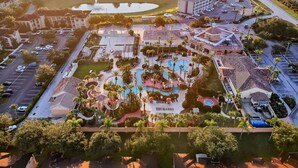 An aerial view of a hotel with a swimming pool, multiple parking lots, and surrounding greenery. - Laura's Villa at Regal Palms (Davenport)