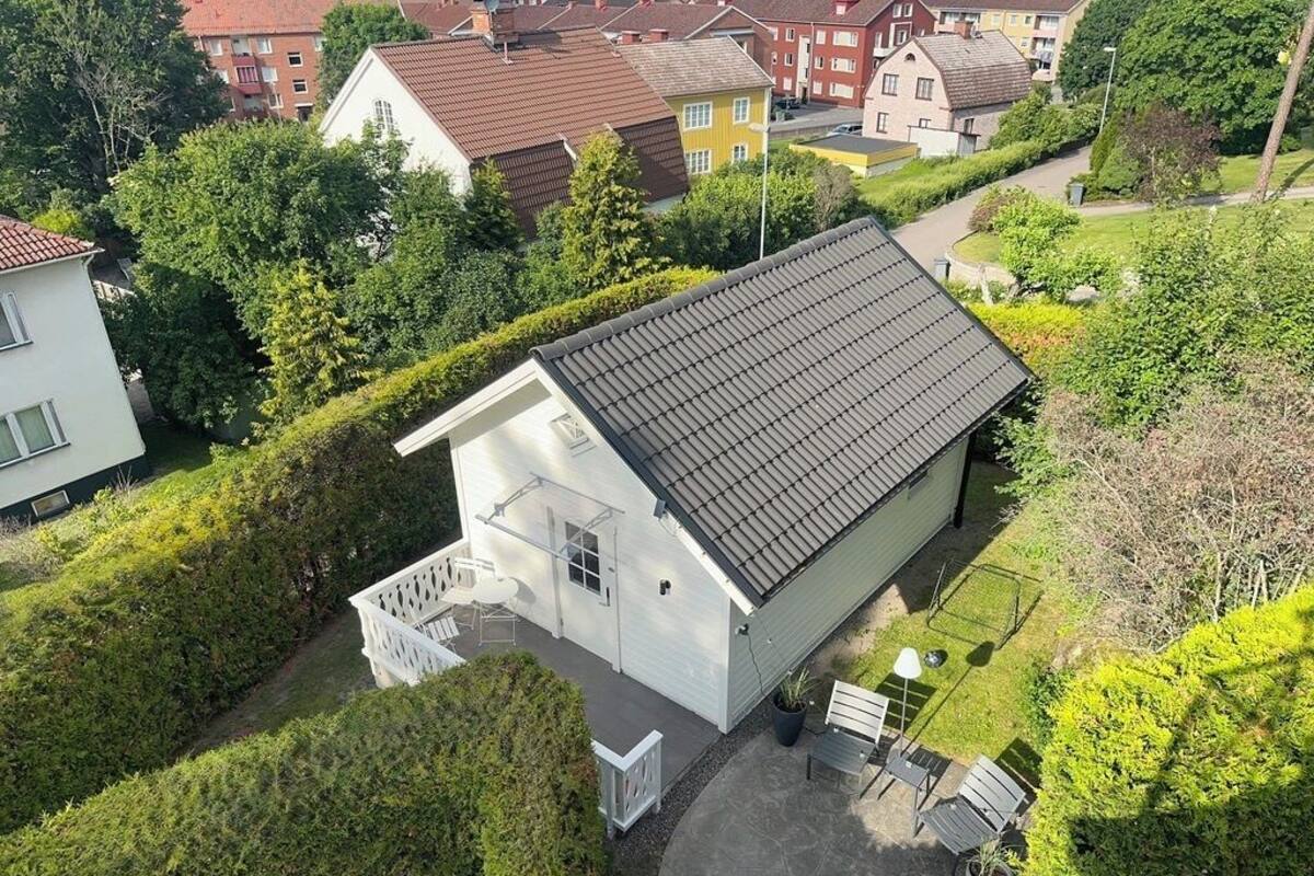Ein zweistöckiges Haus mit Ziegeldach, einer kleinen Veranda und einem gepflegten Garten.