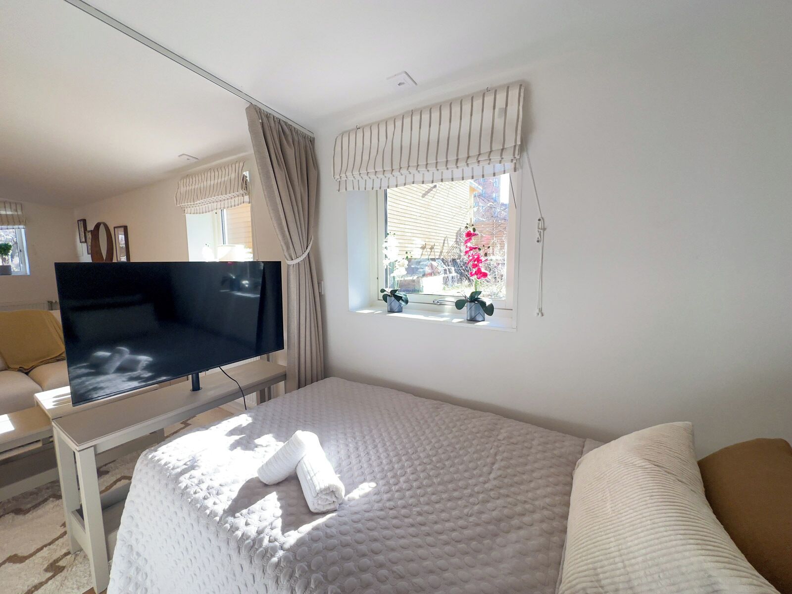 Habitación de hotel con cama, televisor, ventana con cortinas y vistas al exterior.
