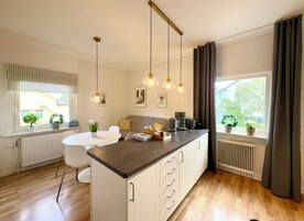 A modern kitchen with a central island, pendant lighting, and a view of the outdoors.