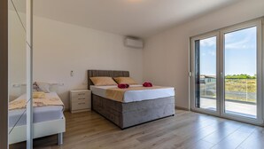 Et soveværelse med seng, sengeborde, et skab og en skydedør til en balkon.