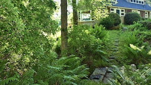 Una casa circondata da una vegetazione rigogliosa e un vialetto in pietra che conduce all'ingresso.