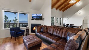 Uma sala de estar ampla com um sofá de couro estofado grande, uma poltrona azul e uma lareira.