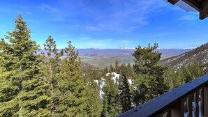 Uma varanda com vista para uma paisagem montanhosa, incluindo picos nevados e florestas densas.