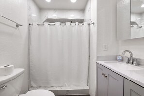 A bathroom with a toilet, a sink, and a shower curtain. - Mile High Mountain - Carson Valley Views (Stateline)