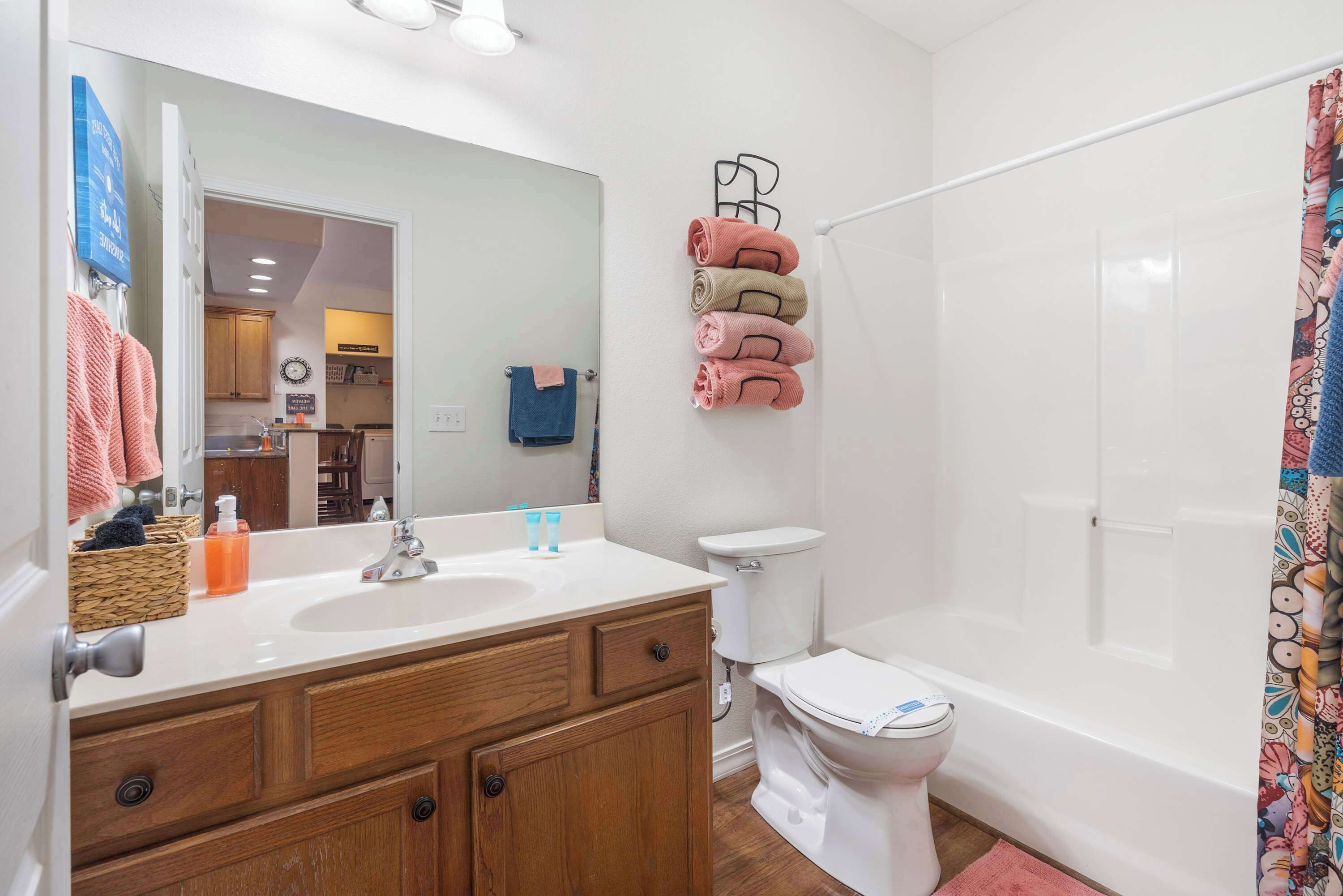 Une salle de bain avec un lavabo blanc, un meuble-lavabo en bois, des toilettes et une douche.