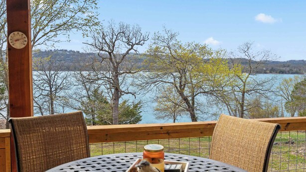 A table with a tray of food and a birdcage, overlooking a lake with trees and hills. - Lakefront Sanctuary II at Indian Point (Branson)