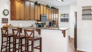 A modern kitchen with wooden cabinets, a central island with bar stools, a microwave, and a coffee maker. - Lakefront Sanctuary II at Indian Point (Branson)