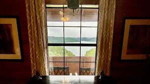 Una habitación con un ventanal grande, cortinas y vistas a un paisaje.