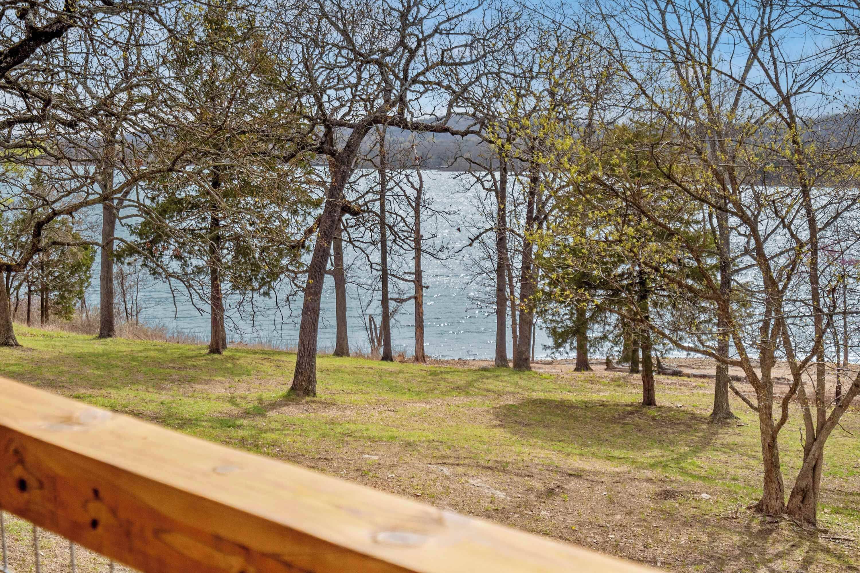 Vista de un lago con árboles y una cerca de madera al frente.