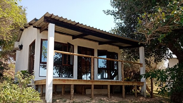 Un edificio a piano terra con una veranda in legno e ampie finestre.