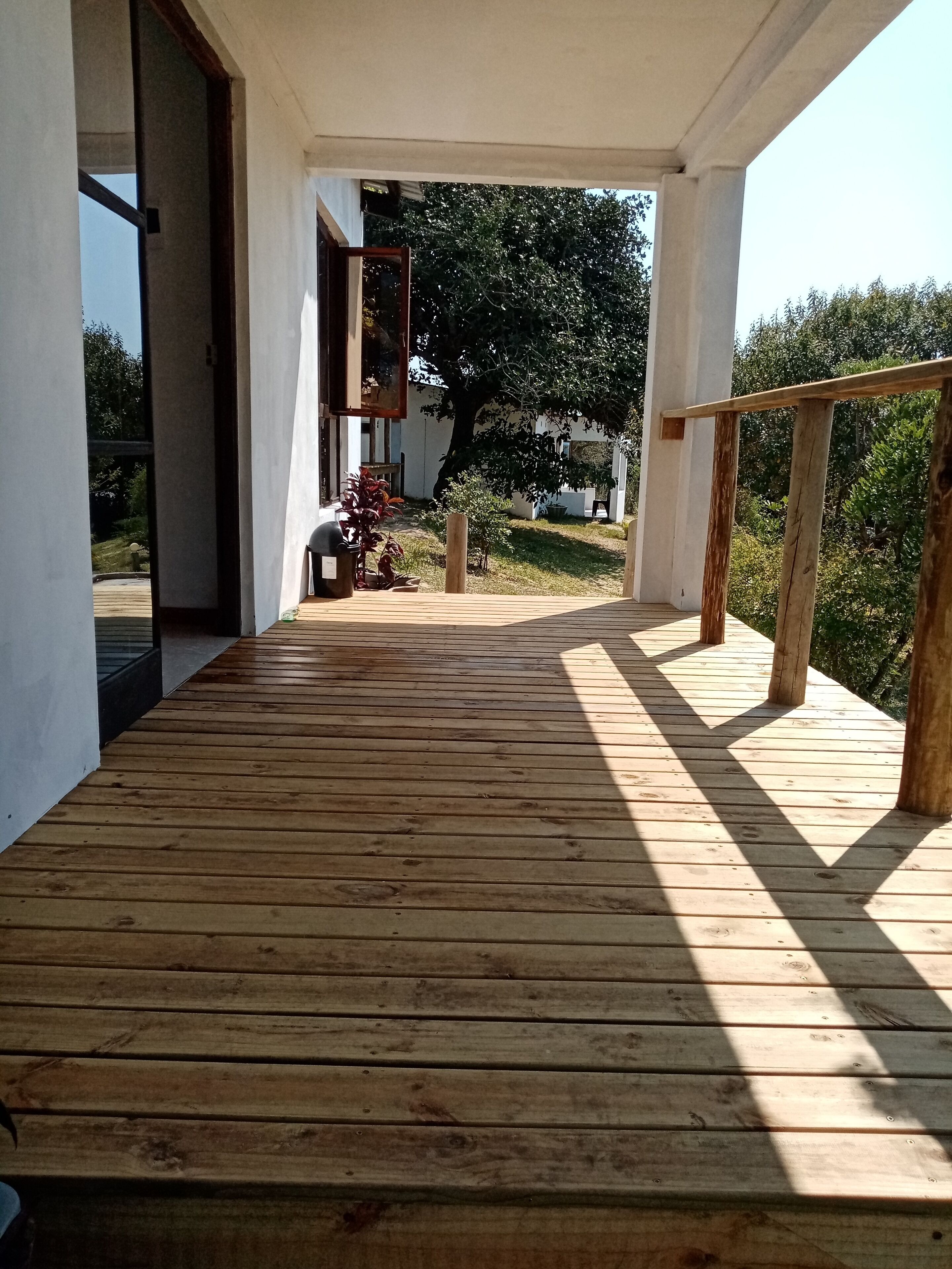 A wooden deck with a view of a garden and a building in the background.