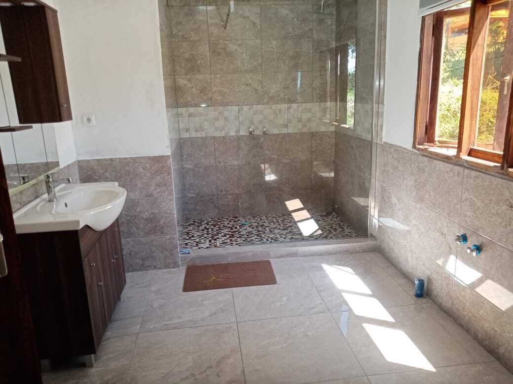 A bathroom with a shower, sink, and wooden cabinets.