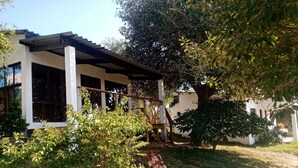 Una casa con un portico coperto, un piccolo giardino e un albero.