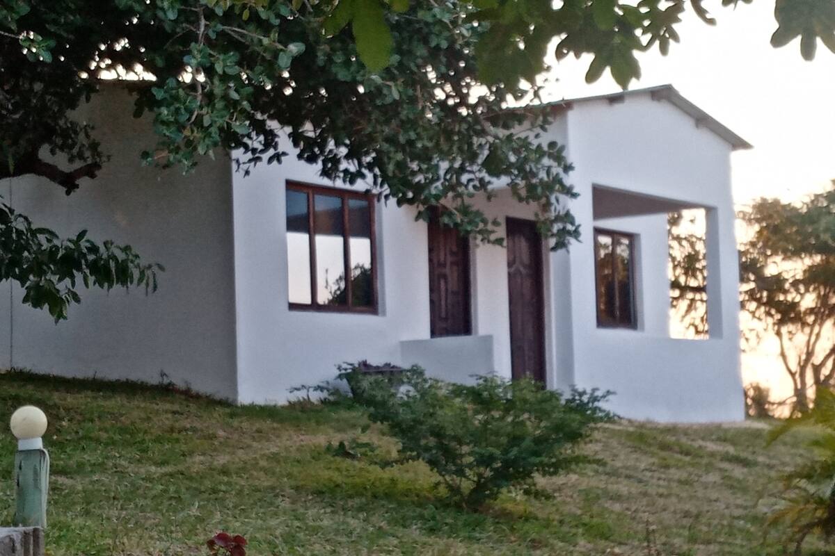 Ein modernes, weißes Gebäude mit flachem Dach, einer kleinen Veranda und einer Tür.