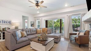 A spacious living room with a grey sectional sofa, a coffee table, and a ceiling fan. - New Lakeside Haven - Picturesque (Branson)