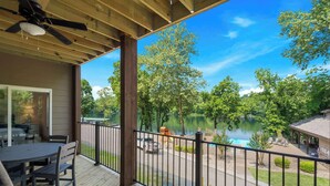 A wooden deck with a table and chairs, overlooking a lake with a playground and a boat dock. - New Lakeside Haven - Picturesque (Branson)