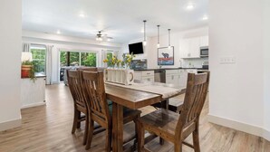 A modern kitchen with white cabinets, a dining table with wooden chairs, and a large window. - New Lakeside Haven - Picturesque (Branson)