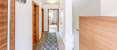 A hallway with wooden doors, a patterned floor, and a wardrobe.