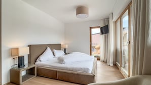 A hotel room with a bed, bedside lamps, a TV, and a view of the outside. - Pool-chalet - Zentral in Seefeld (Seefeld in Tirol)