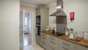 A modern kitchen with a built-in oven, a stainless steel range hood, and a wooden countertop. - 2 bedroom accommodation in Reepham (Reepham)
