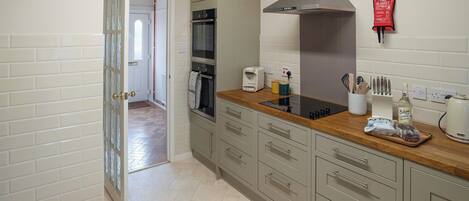 A modern kitchen with a built-in oven, a stainless steel range hood, and a wooden countertop.