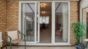 A covered patio area with a sliding glass door leading to an indoor dining space. - 2 bedroom accommodation in Reepham (Reepham)