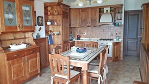 Uma cozinha tradicional com armários de madeira, uma mesa de jantar com cadeiras e uma ilha central.