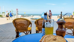 A seaside table with a bottle of Blanched Namur beer, a glass of beer, and a bread roll. - Lovely apartment in Oostende with WiFi (Oostende)