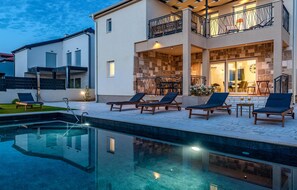 Ein modernes Haus mit Pool, Außenbereich und einer Stein-Fassade.