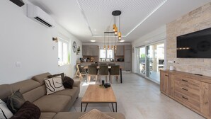 Een moderne woonkamer met een bank, een salontafel en een televisie op een houten kast.