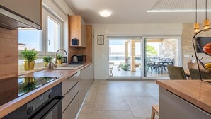 Een moderne keuken met een groot raam, houten keukenkastjes en een inbouwoven.
