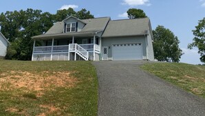 A two-story house with a front porch, a garage, and a driveway leading to the house.