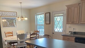 A kitchen with a central island, wooden chairs, a dining table, and a chandelier.