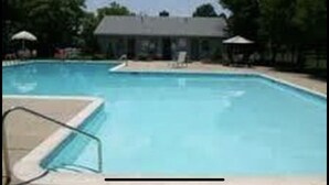 A swimming pool with a lounge area and a building in the background.