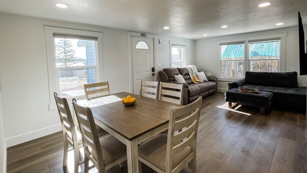 Amplia sala de estar con mesa de comedor, sillas de madera, sofá y un sofá negro.